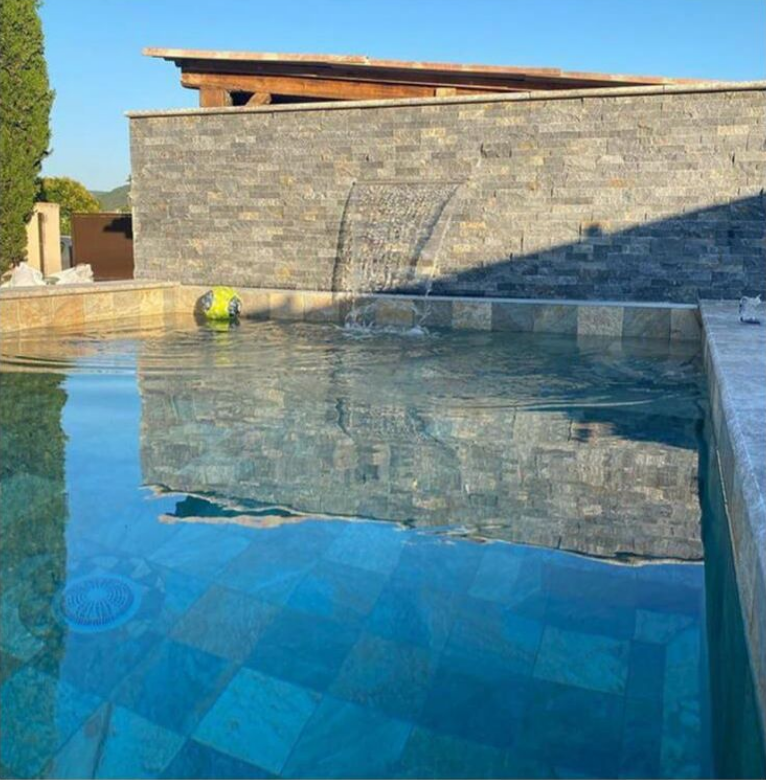Carrelage aspect pierre marron nuances de gris sans motifs 30x60 cm dans espace extérieur piscine bleue revêtement eau cristalline