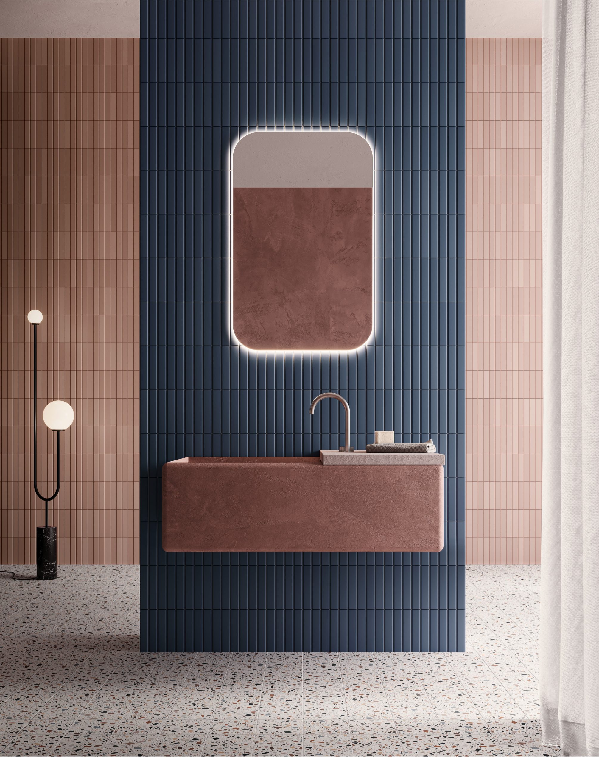 Carrelage uni rose et bleu dans une salle de bain aux murs bleu marine et rose, sol terrazzo, meuble vasque marron, miroir lumineux