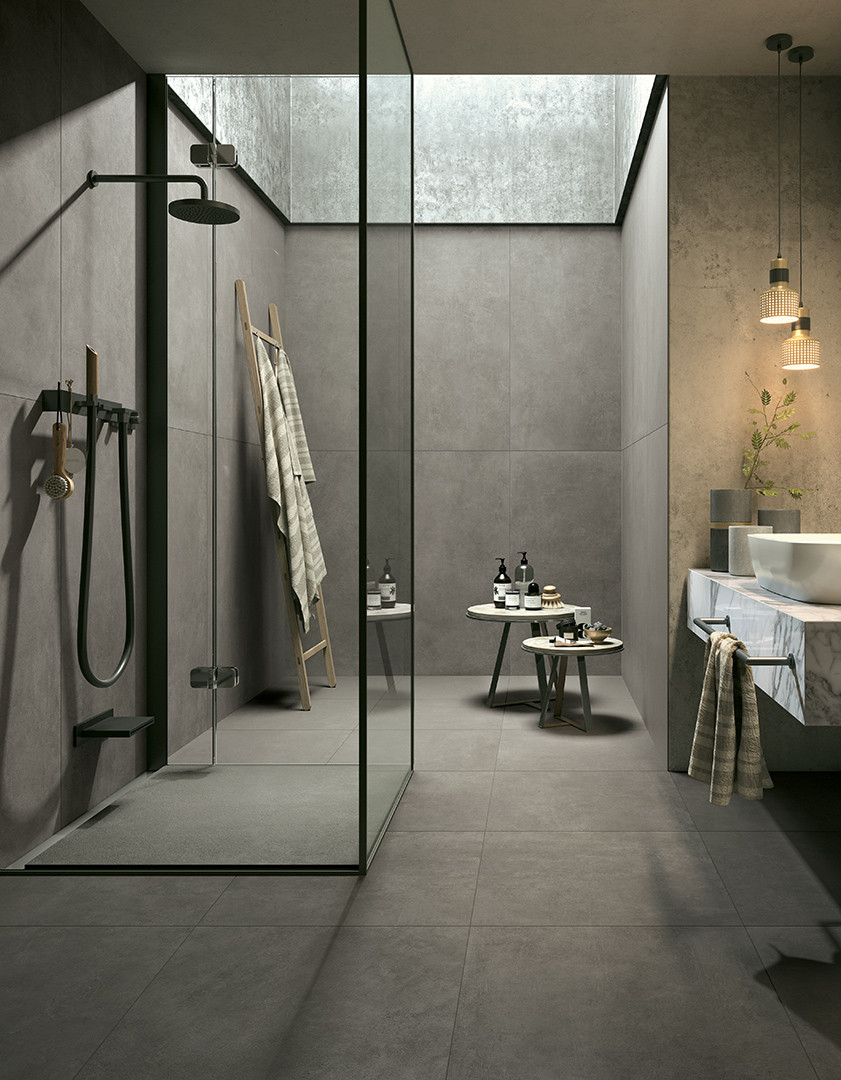 Carrelage effet pierre gris 80x80 cm dans une salle de bain moderne avec meubles en bois clair et notes de vert
