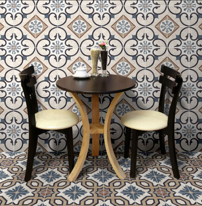 Carreau de ciment multicouleur motifs traditionnels 20x20 cm dans un café avec des murs et sol assortis, table en bois marron, chaises noires et beige, vase sur la table