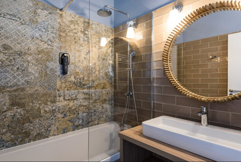 Carrelage effet tissu beige marbré 50x100 cm dans une salle de bain tons marron avec miroir rond et douche moderne
