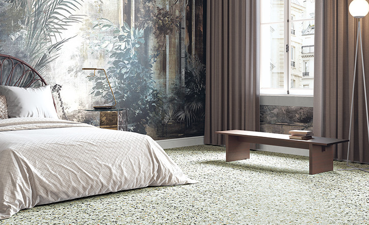 Terrazzo multicouleur 60x60 cm dans une chambre beige avec lit, banc, plantes et lampe