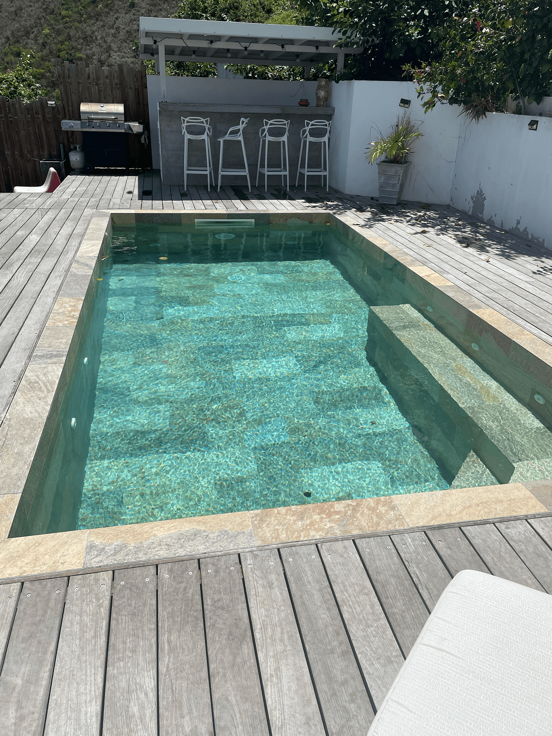 Carrelage effet pierre beige 30x60 cm autour piscine avec terrasse bois et coin barbecue blanc