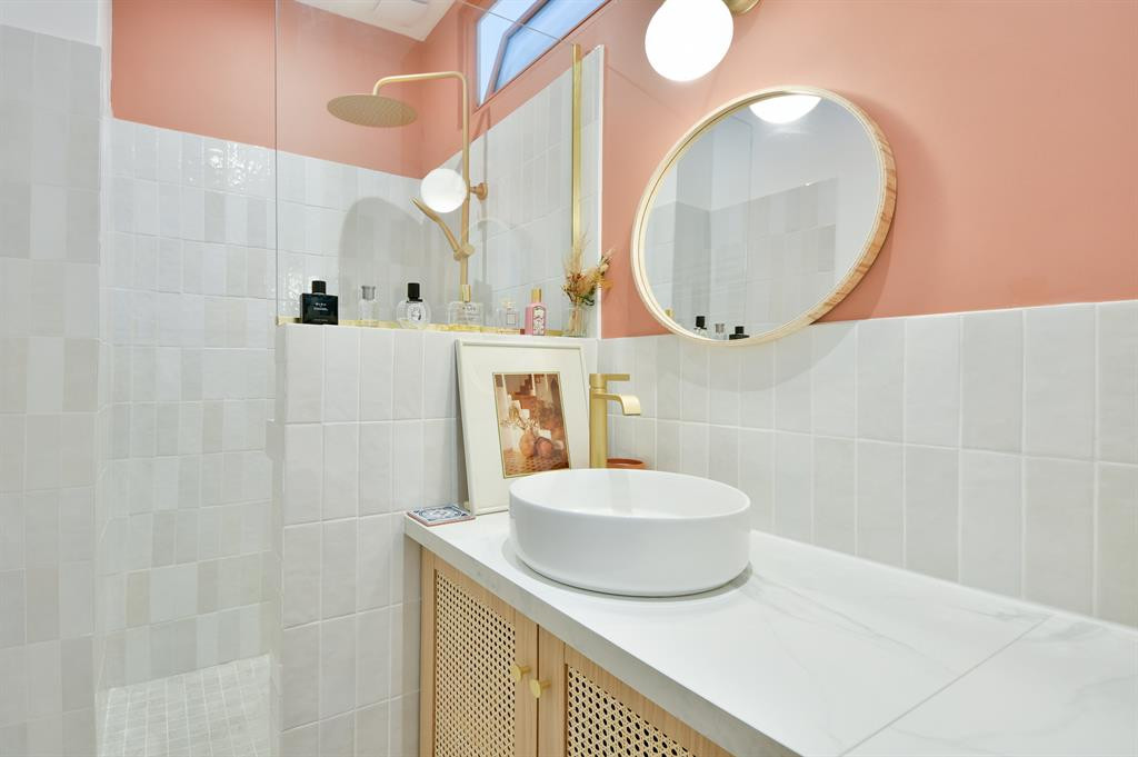 Carrelage Zellige blanc brillant 6,5X20 dans une salle de bain rose avec évier rond et accessoires dorés