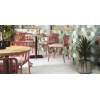 Carrelage uni blanc dans une salle à manger aux chaises rouges, mur multicolore, plantes vertes, éclairage naturel