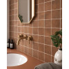 Zellige rouge brillant 10x10 cm sur le mur de la salle de bain tons neutres avec vasque, miroir et luminaire suspendu