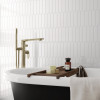 Carrelage uni blanc dans une salle de bain épurée avec baignoire noire et blanche, accents dorés, serviettes et accessoires rela