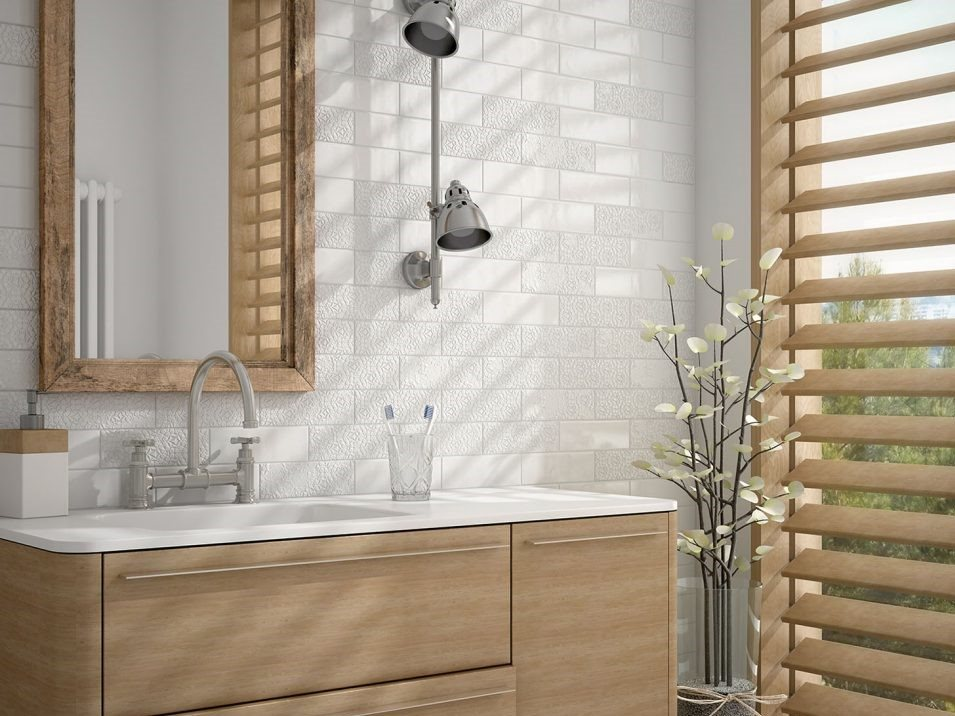 Carrelage uni blanc avec motifs discrets dans une salle de bain épurée aux meubles bois clair et accessoires chromés