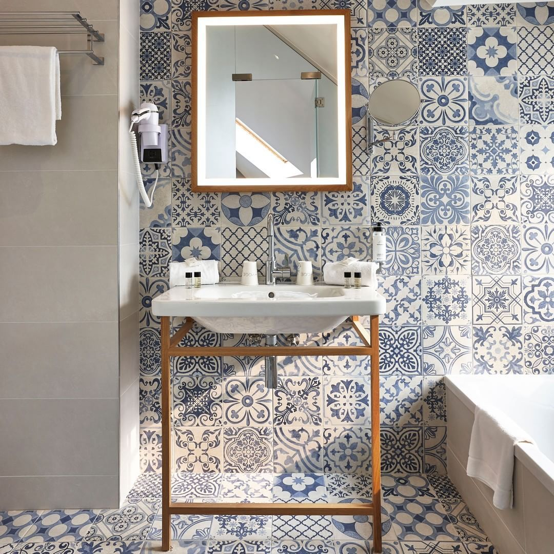 Carreau de ciment bleu motifs variés 45x45 cm dans une salle de bain tons neutres avec miroir et lavabo