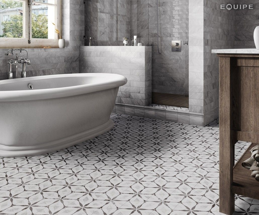 Carreau de ciment gris à motifs géométriques sur le sol dune salle de bain ton sur ton avec baignoire et murs en marbre gray