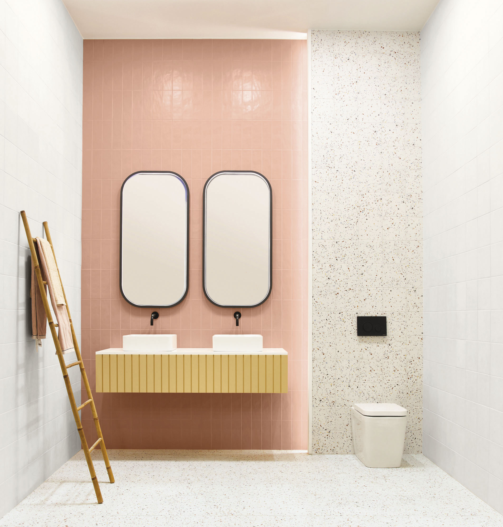Terrazzo blanc avec éclats colorés 20x20 cm dans une salle de bain tons roses et blancs avec meuble vasque échelle décorative et miroirs ovales