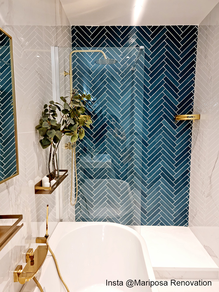 Zellige bleu nuances de cyan chevron dans salle de bain contemporaine, murs blancs, accents dorés, baignoire blanche