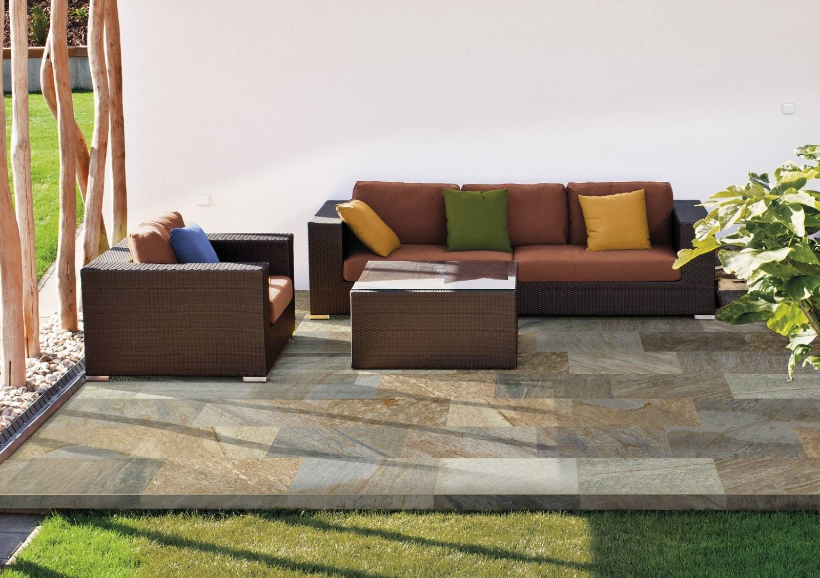 Carrelage effet pierre marron nuances beige 30x60 cm sur terrasse avec mobilier de jardin et végétation
