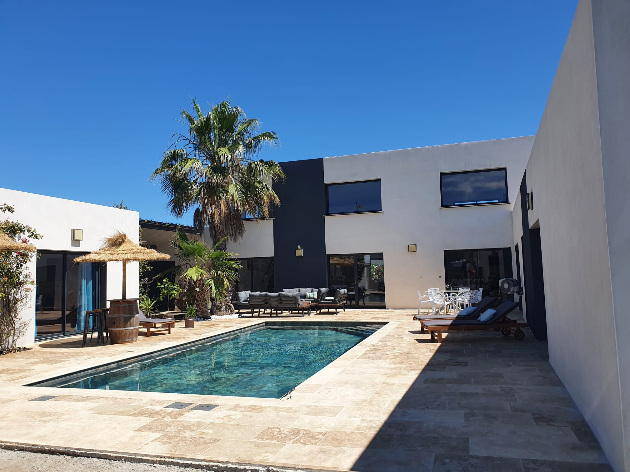 Carrelage aspect pierre couleur terracotta dans un espace extérieur combiné avec une piscine et mobilier de jardin contre une maison moderne